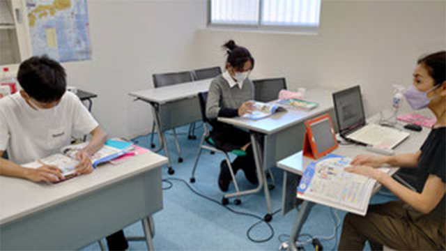 日本語を教える教師と生徒2人の授業風景